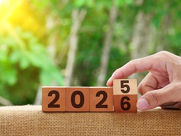 wooden blocks showing 2025 with a hand changing it to 2026